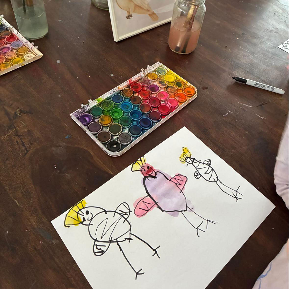 A photograph of a child’s painting of 3 figures